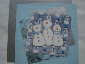 Handgjort julkort med snögubbar i blåa nyanser