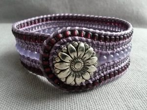 Brett fem raders handsytt läderarmband i lila med blomknapp