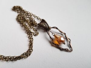 Justerbart halsband med ett trådslöjds hänge i brons